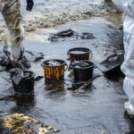 Workers remove crude oil from a beach