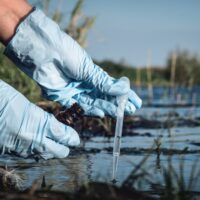 Water pollution concept. Woman scientist takes a water sample from polluted pond. Water pollution concept. Woman scientist takes a water sample from polluted pond.