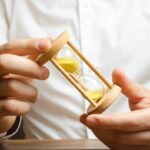 Hourglass in the hands of a businessman in a white shirt. Planning time and reducing business costs. Catch all and do all planned things. Time saving. Businessman in thought. The minimum wage per hour Hourglass in the hands of a businessman in a white shirt. Planning time and reducing business costs. Catch all and do all planned things. Time saving. Businessman in thought. The minimum wage per hour