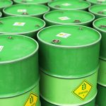 Creative abstract ecology, alternative sustainable energy and environment protection saving business concept: 3D render illustration of the group of green stacked metal biofuel drums or biodiesel barrels in the industrial storage warehouse with selective focus effect