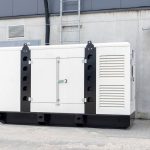 White auxiliary diesel generator for emergency power supply. Industrial generator connected to the control panel by a cable wire. Backup power supply of the generator.