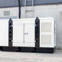 White auxiliary diesel generator for emergency power supply. Industrial generator connected to the control panel by a cable wire. Backup power supply of the generator. White auxiliary diesel generator for emergency power supply. Industrial generator connected to the control panel by a cable wire. Backup power supply of the generator.
