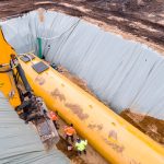 Worker installing a huge underground fuel tank, aerial Worker installing a huge underground fuel tank, aerial