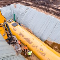 Worker installing a huge underground fuel tank, aerial Worker installing a huge underground fuel tank, aerial